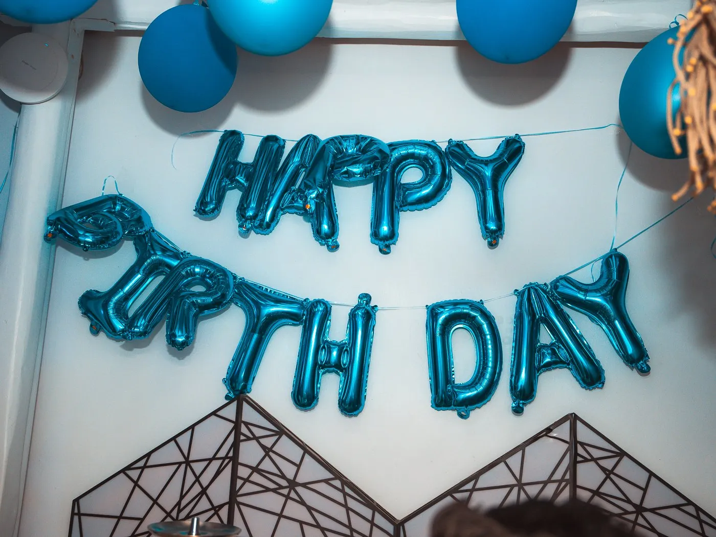 A Happy Birthday balloon display on the whitewashed wall at BAO'S