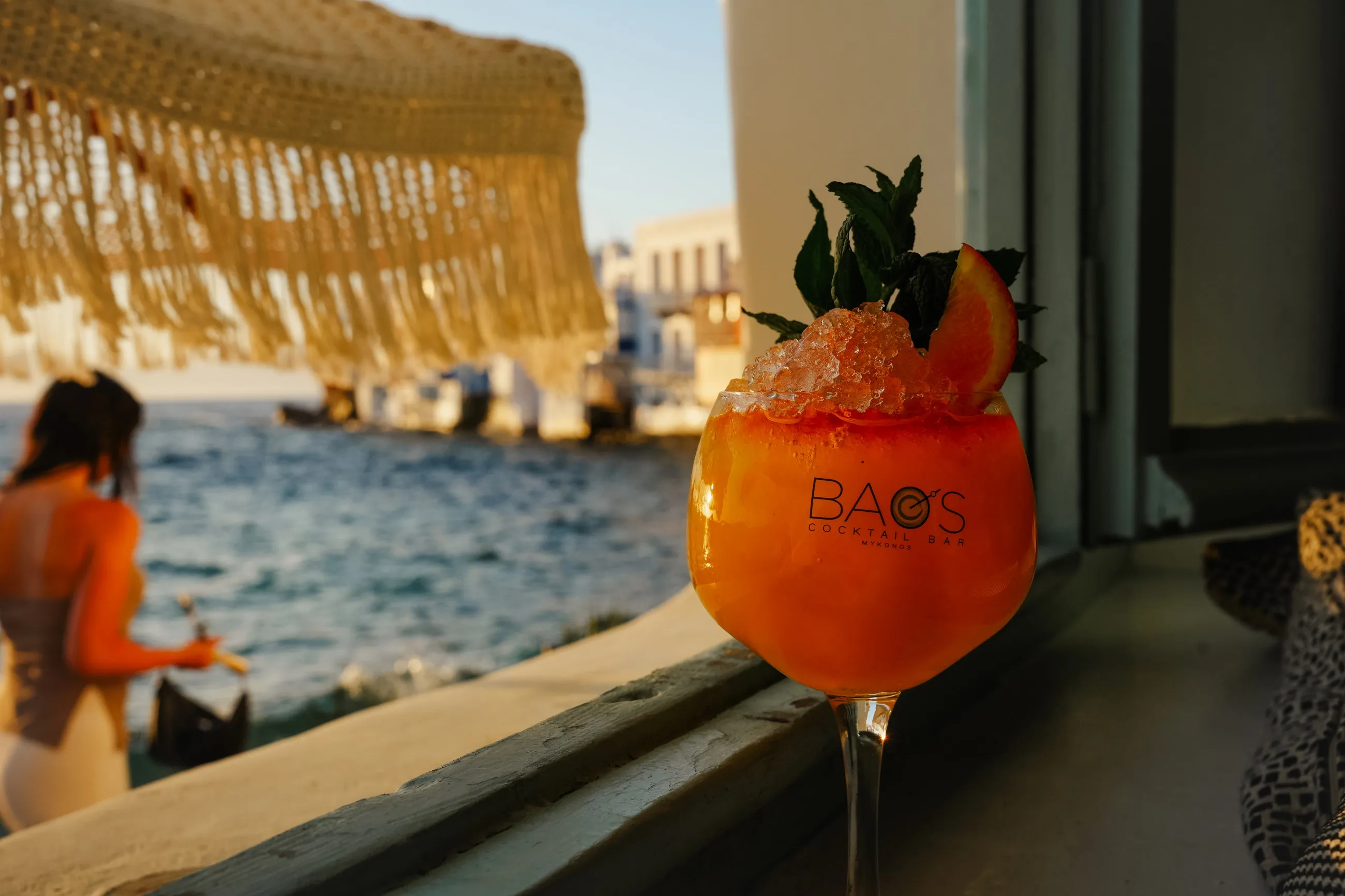 A BAO'S cocktail on the ledge beneath a macramé parasol, the houses of Little Venice behind