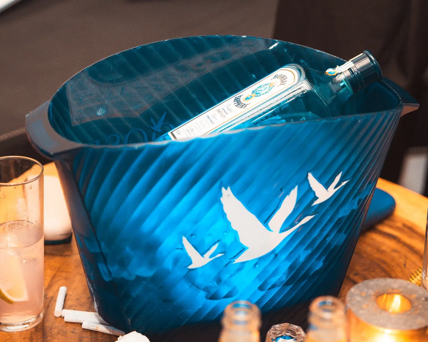 An ice bucket and a bottle on a table at BAO'S, drinks and a lit candle beside it