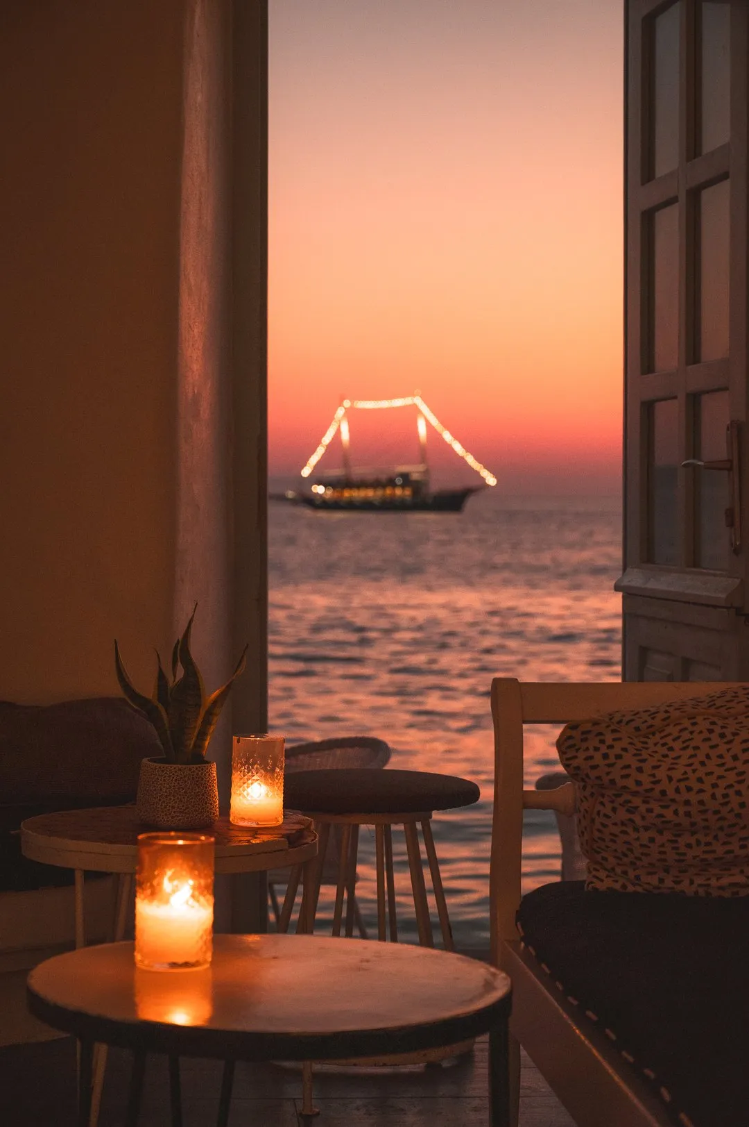 Der Rotonda Table im BAO'S im warmen Abendlicht, vor dem offenen Bogenfenster zum Meer
