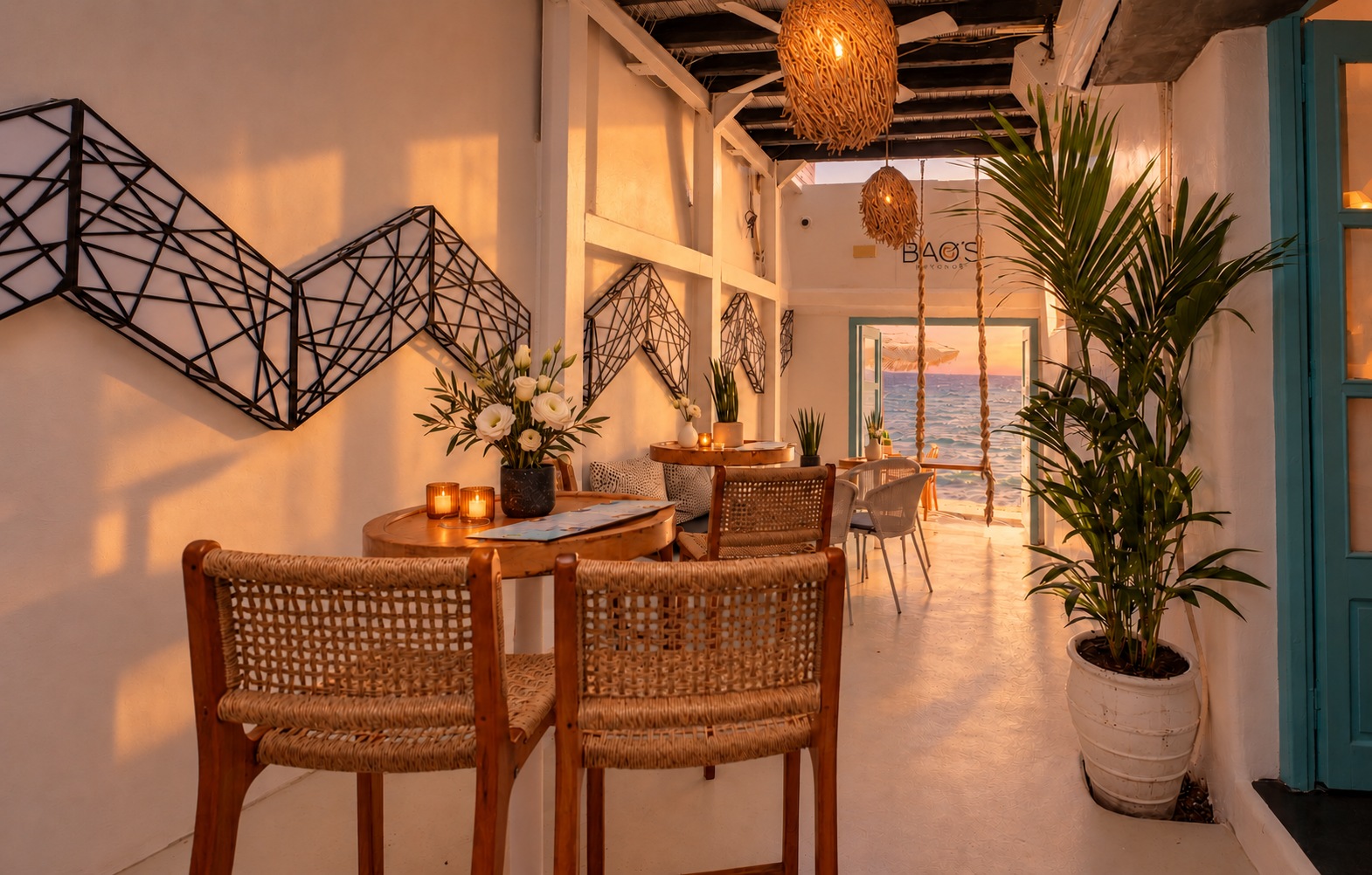 A mesma passagem na luz do pôr do sol, com as luminárias acesas e cor quente nas paredes brancas, o mar ainda visível na porta