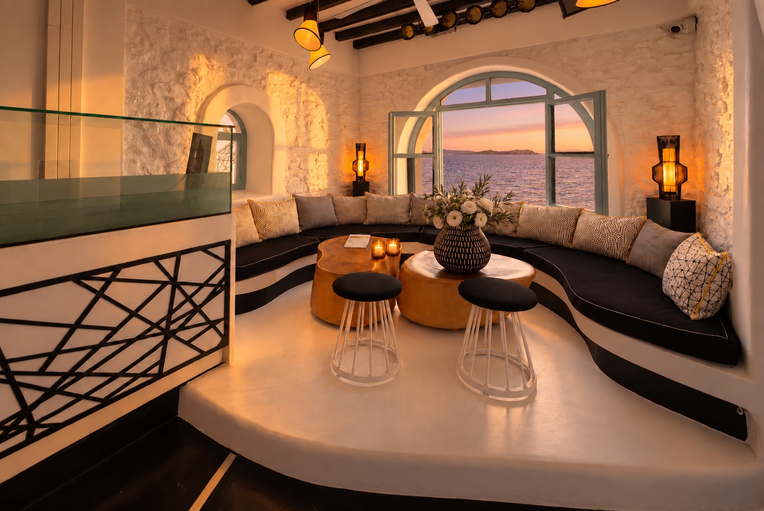 Der The Rotonda Table vom Geländer aus bei Sonnenuntergang, Kerzen auf den Tischen und warmes Licht auf der Steinwand